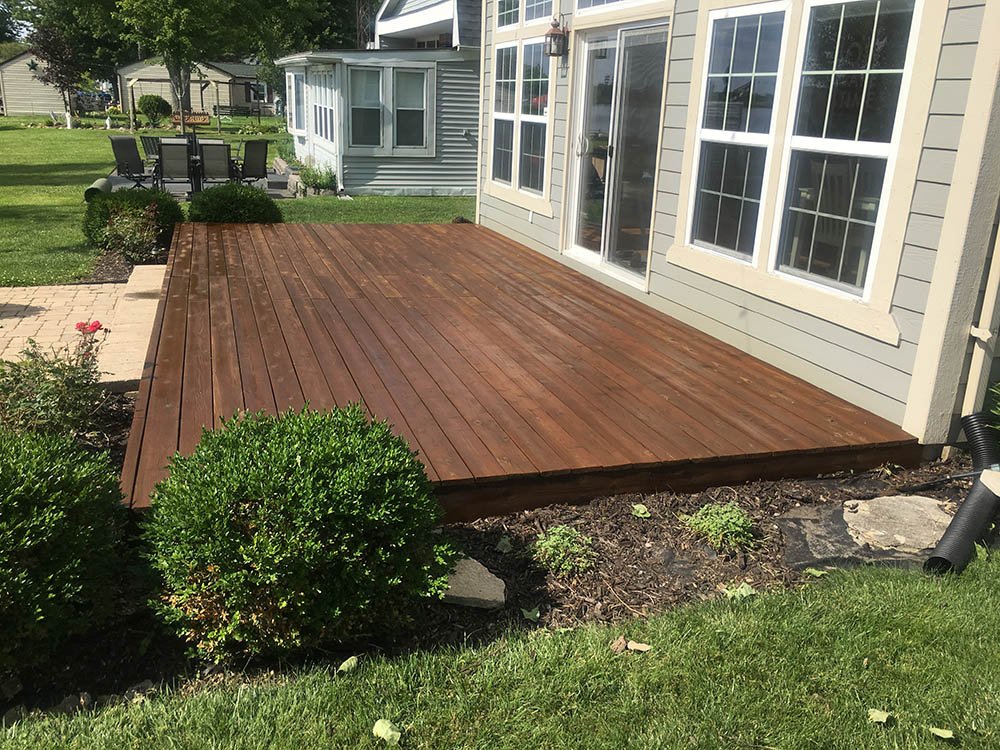 wooden deck behind blue home with small bushes