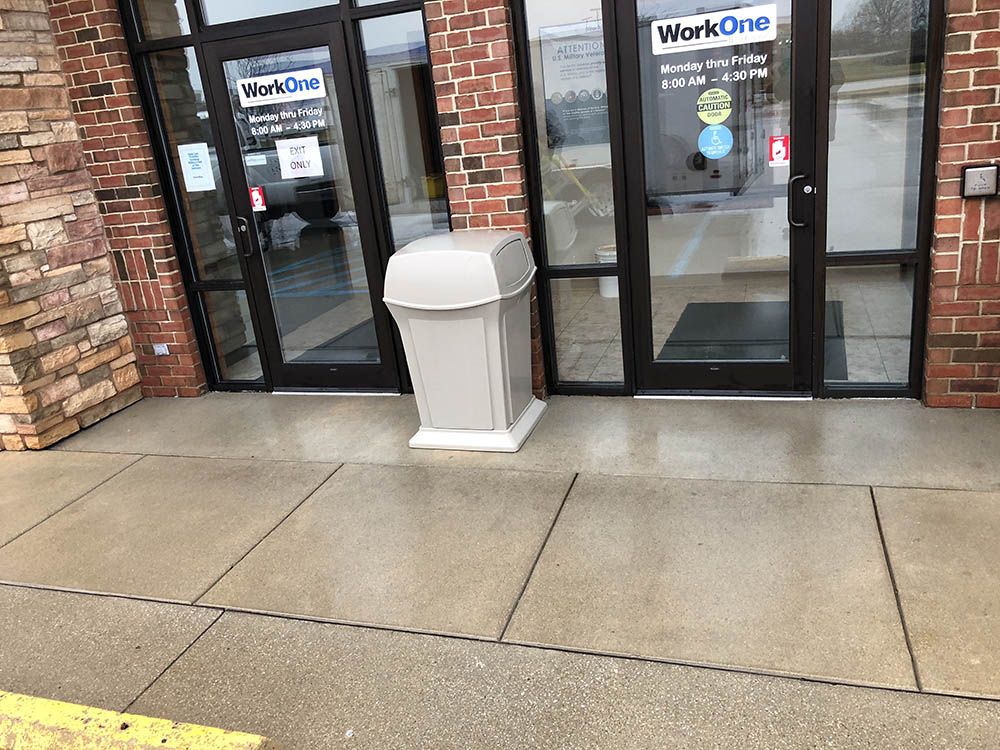 commercial brick building with gray trash can