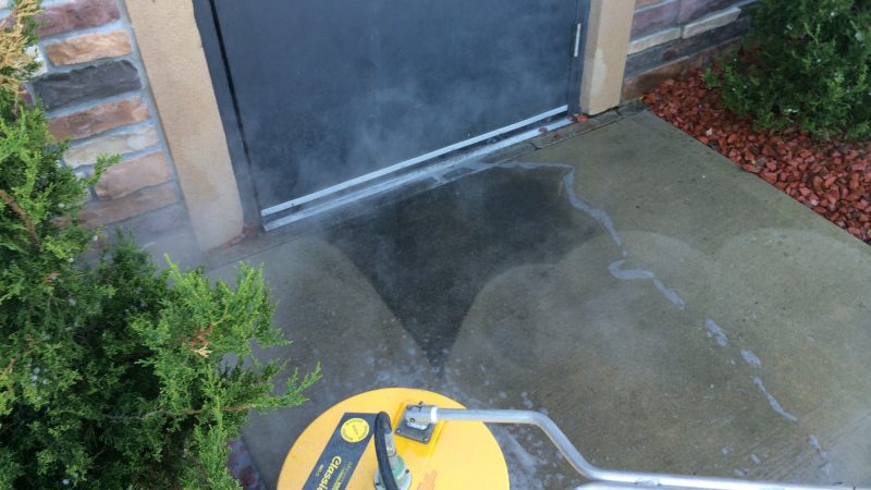yellow pressure washer cleaning patio on home
