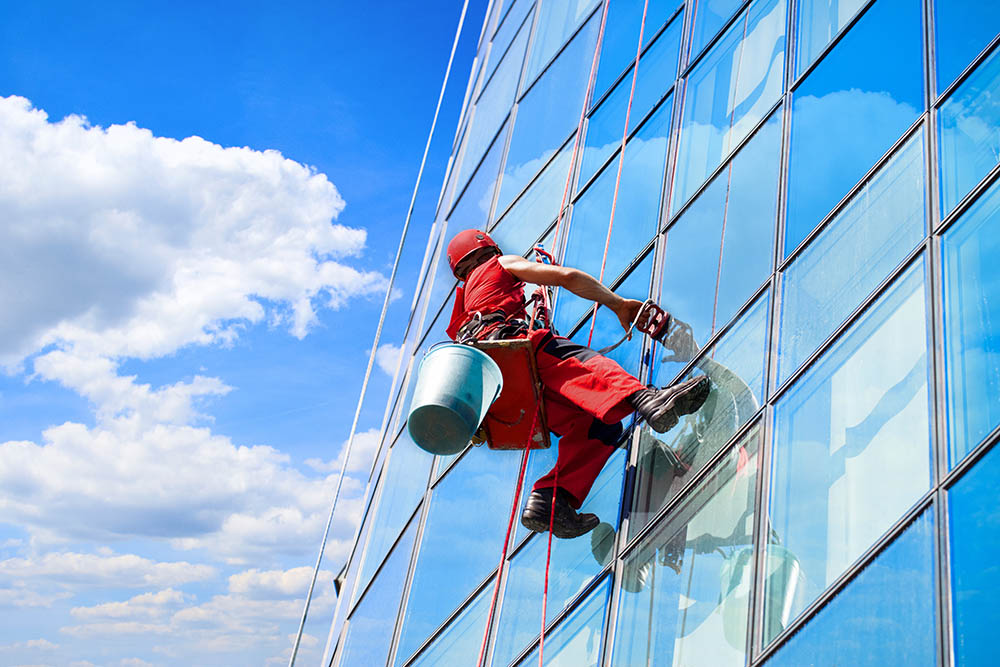 window cleaning professional cleaning high rise windows in red uniform