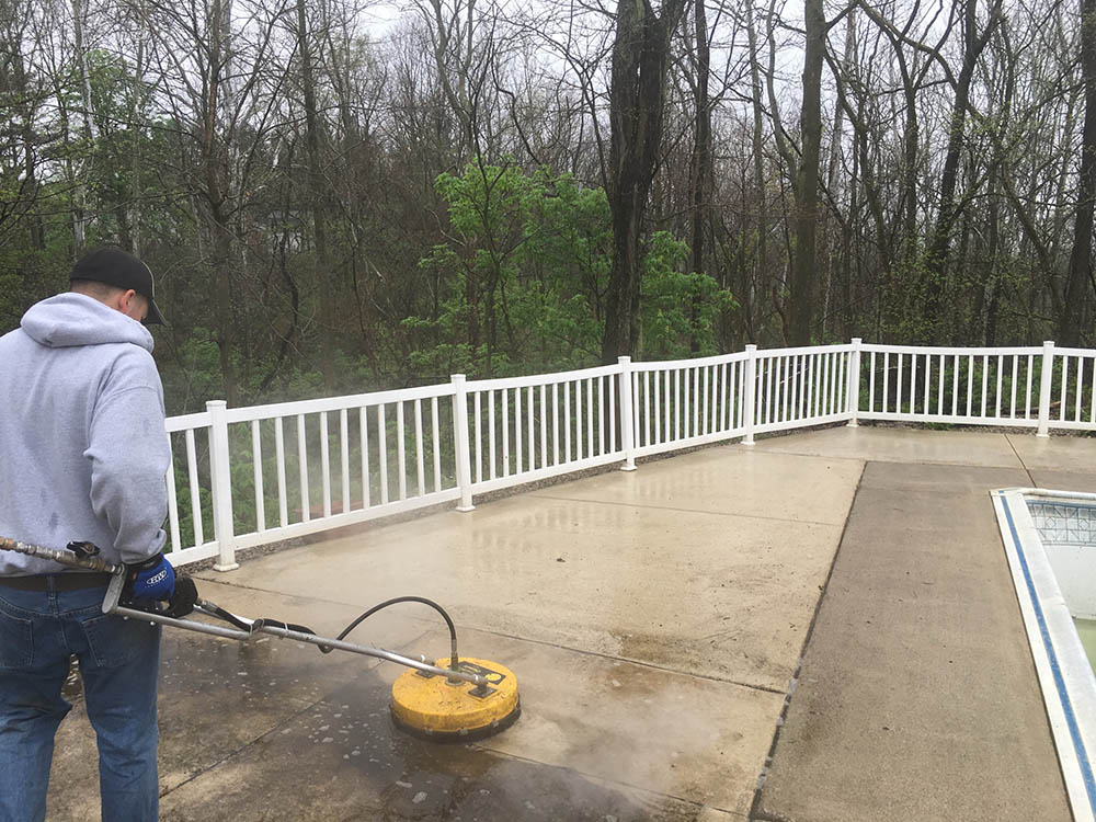 pressure washing professional cleaning concrete around pool